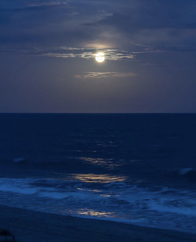 Full moon over a dark ocean shore